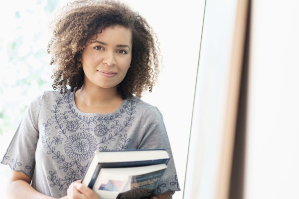 Portrait of young woman holding books.