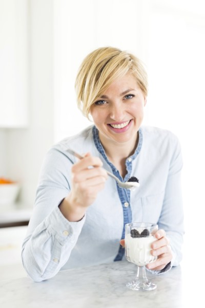 Portrait of woman eating yogurt with blackberries