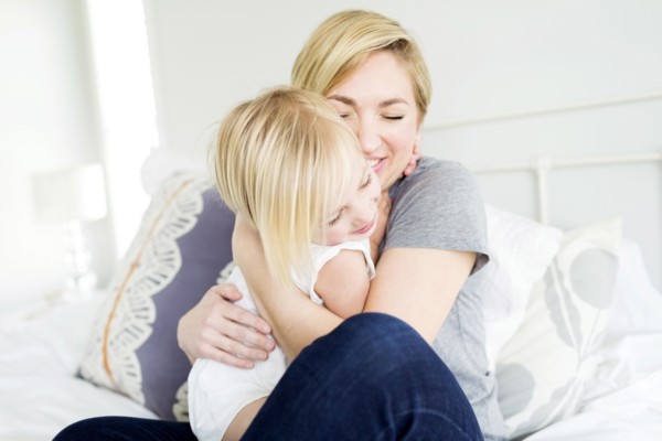 Woman hugging daughter (2-3) in bedroom