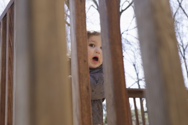 Portrait of girl hiding behind fence