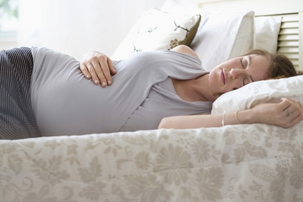 Pregnant woman sleeping in bed.