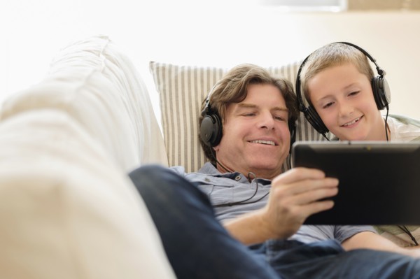 Man using tablet pc with his son (8-9) on sofa.