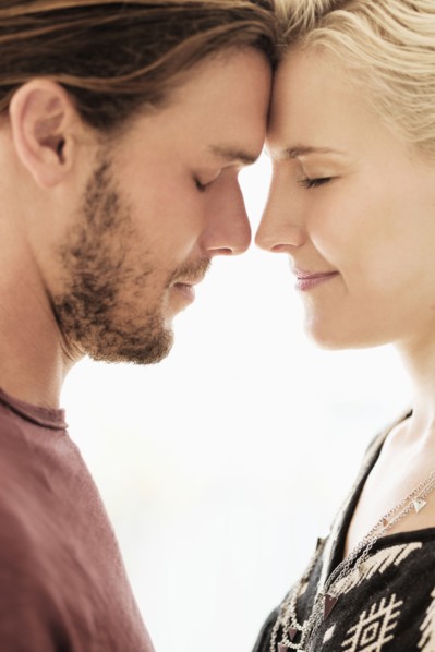 Couple rubbing noses on white background.