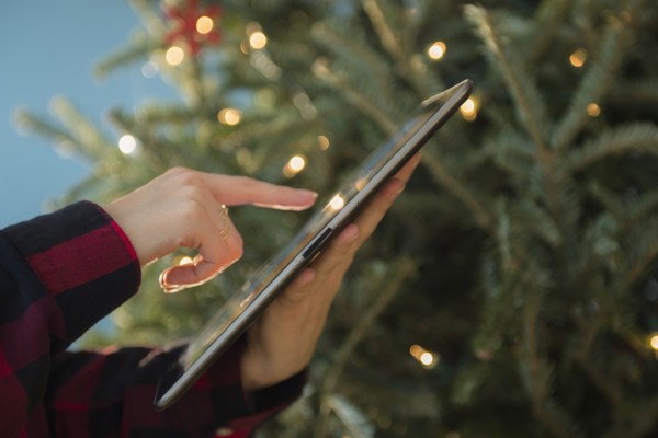 Person using tablet near Christmas tree