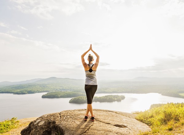 Rear view of young woman practicing yoga in front of lake