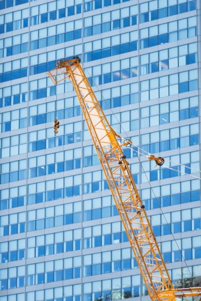 Low angle view of crane against skyscraper