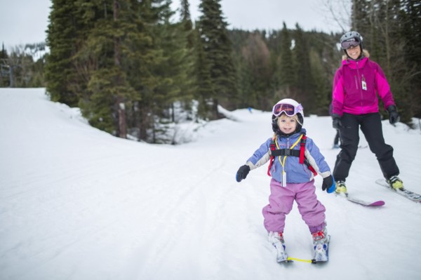 Little girl (2-3) learning skiing with mother