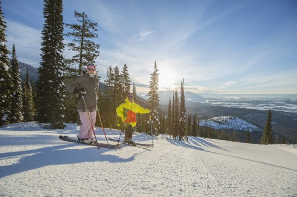 Couple standing on ski slope at sunlight