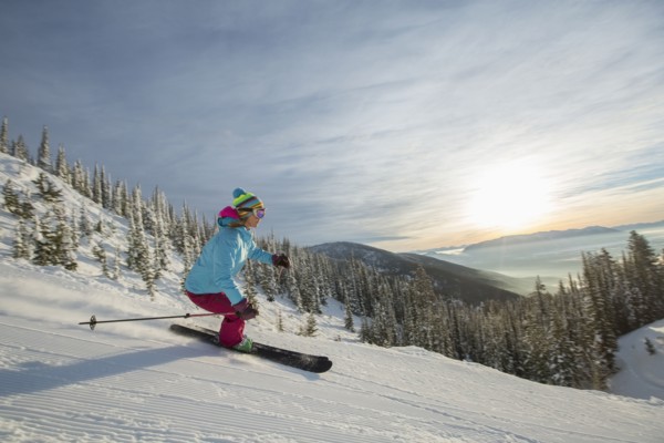 Mature woman on ski slope at sunset