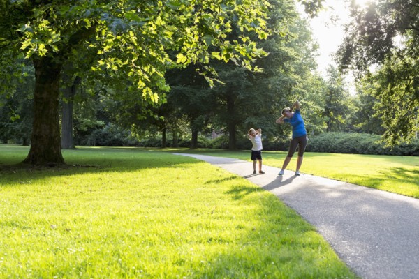 Mother and son (12-13) exercising in park