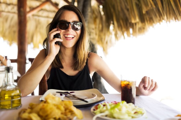 Woman by table, using phone