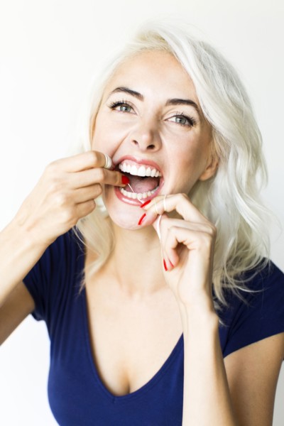 Studio shot of woman using dental floss