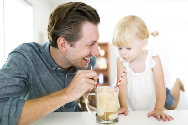Father drinking milkshake with daughter (2-3)