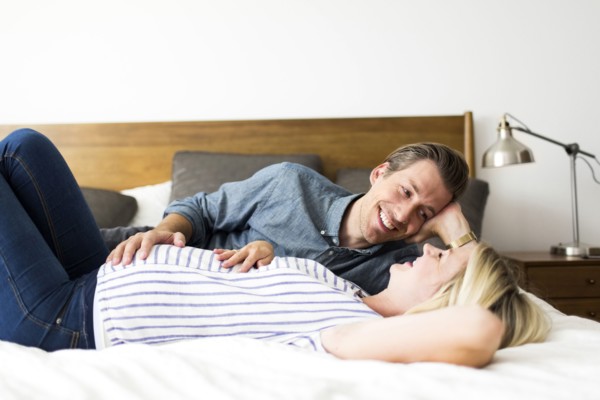 Husband lying down on bed with pregnant wife