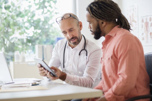 Doctor giving consultation to patient using digital tablet.