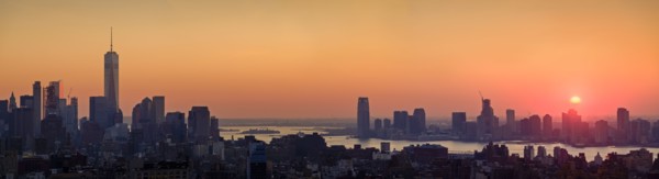 Waterfront cityscape under golden sky at sunset. New York City, New York, USA.