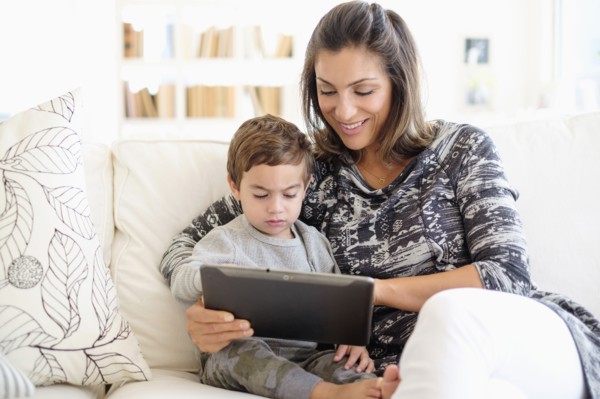 Mother reading with son (2-3) on sofa.