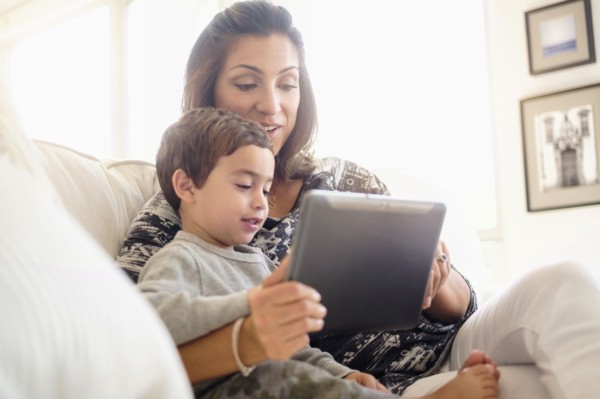 Mother reading with son (2-3) on sofa.