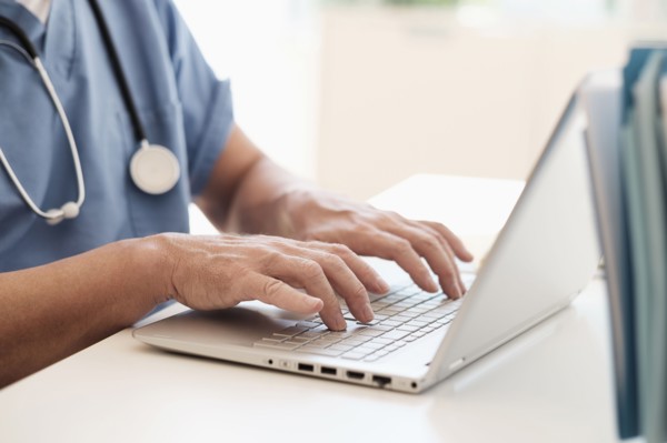 Man in scrubs using laptop.