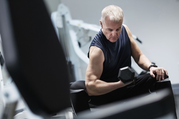 Man exercising with dumbbells on weight bench.