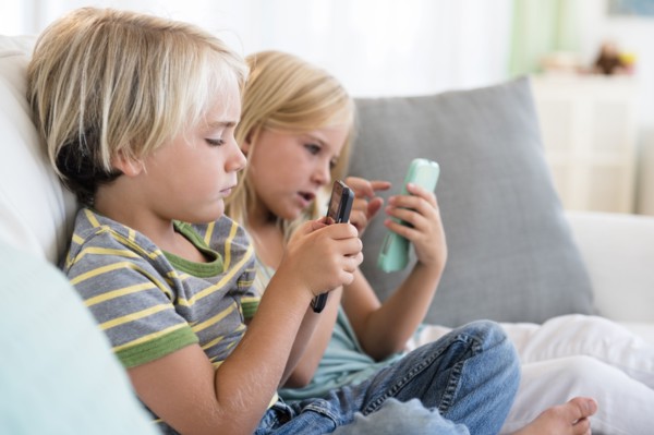 Boy (4-5) and girl (6-7) playing games on smart phones