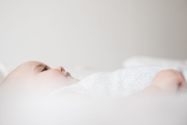 Baby girl (12-17 months) lying down on bed
