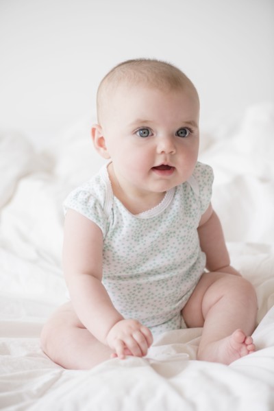 Baby girl (12-17 months) sitting on bed
