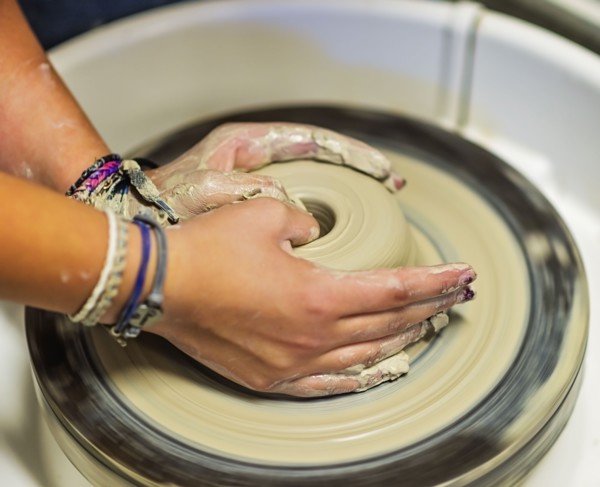 Woman shaping clay bowl on pottery wheel