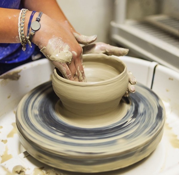 Woman shaping clay bowl on pottery wheel