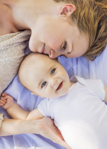 Mother lying down with baby boy (6-11 months)