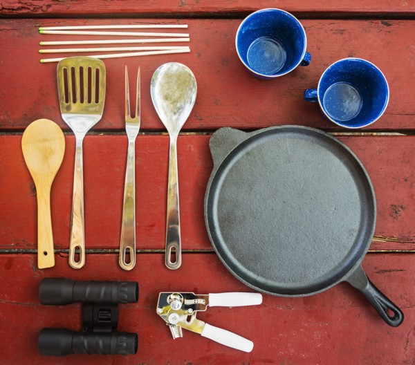 Skillet, cups and cooking utensils on picnic table