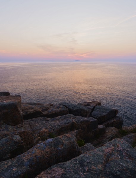 Rocky cliff by sea at sunrise