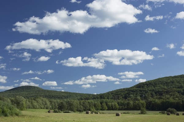 Landscape with field, hay bales and hills