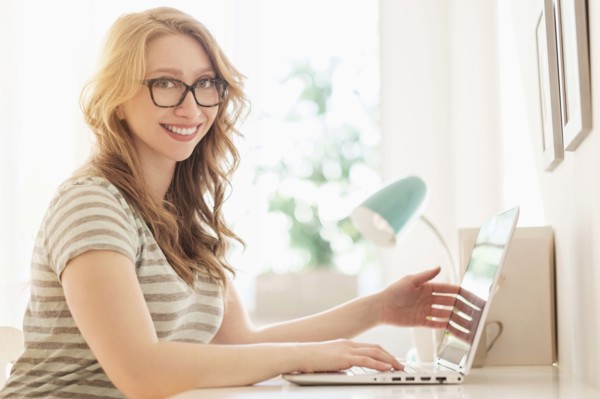 Portrait of young woman working on laptop at home.