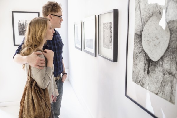 Young couple looking at photographs at museum.