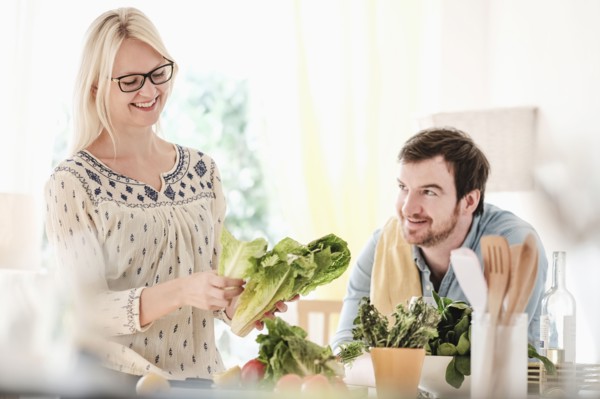 Man and woman in kitchen, smiling.