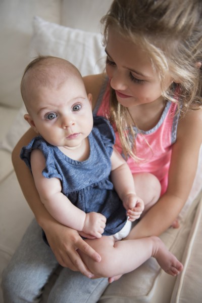 Young girl (6-7) holding baby sister (2-5 months)