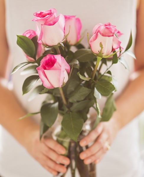 Mid section of woman holding bunch of pink roses