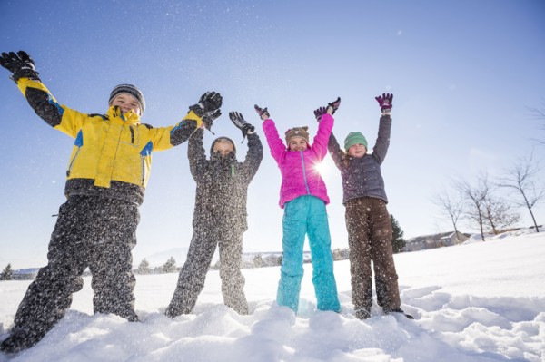 Children (8-9, 10-11) standing in snow with arms raised
