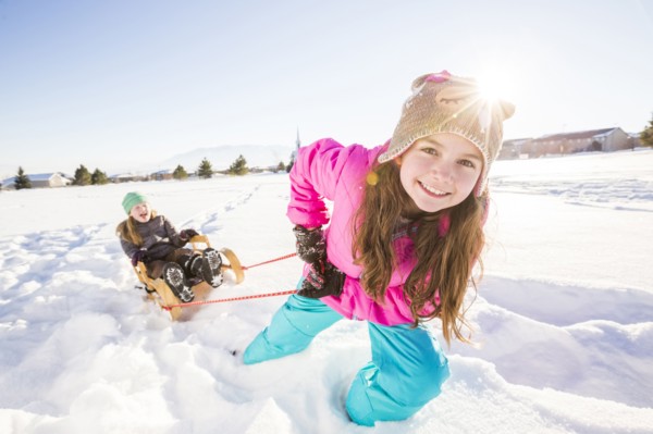 Children (8-9, 10-11) playing with sled in snow