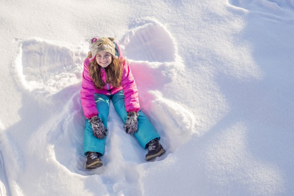 Girl (10-11) in pink jacket sitting in snow