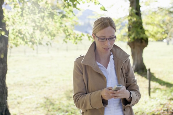 Woman in beige coat using mobile phone