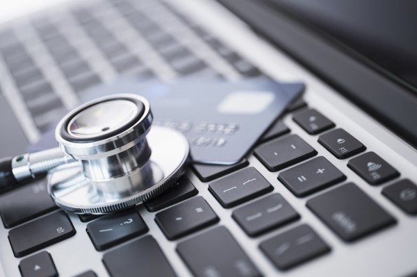 Stethoscope and credit card lying on laptop.