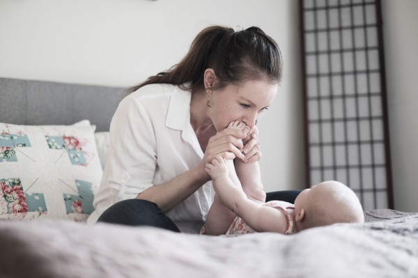 Mother kissing baby daughter's (2-5 months) feet.