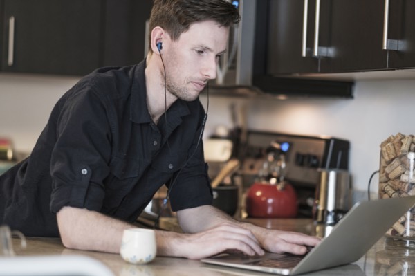 Man working on laptop computer in kitchen.