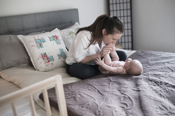 Mother kissing baby daughter's (2-5 month) feet in bedroom.