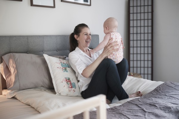 Mother playing with baby daughter (2-5 months) in bedroom.