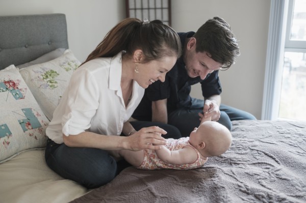 Parents playing with baby daughter (2-5 months) in bedroom.