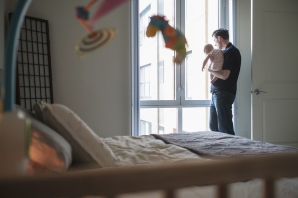 Father looking through window with daughter (2-5 months).