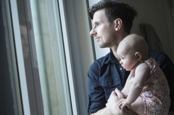 Father looking through window with daughter (2-5 months).